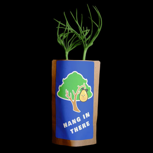 Small plant in a blue pot with a tree and text design on a wooden surface.
