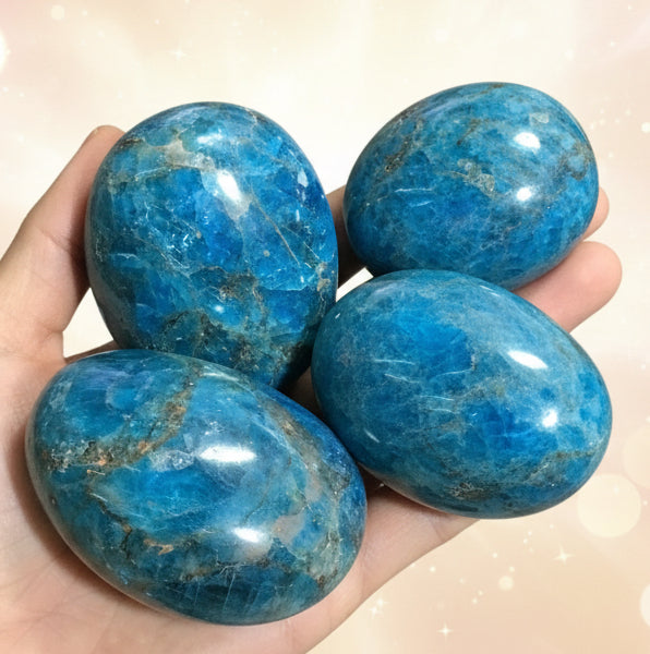 Three blue marbled stones held in a hand against a black background