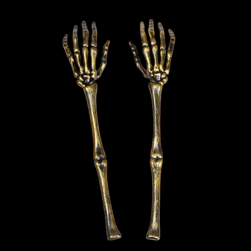 Pair of gold skeleton hand utensils on a white background