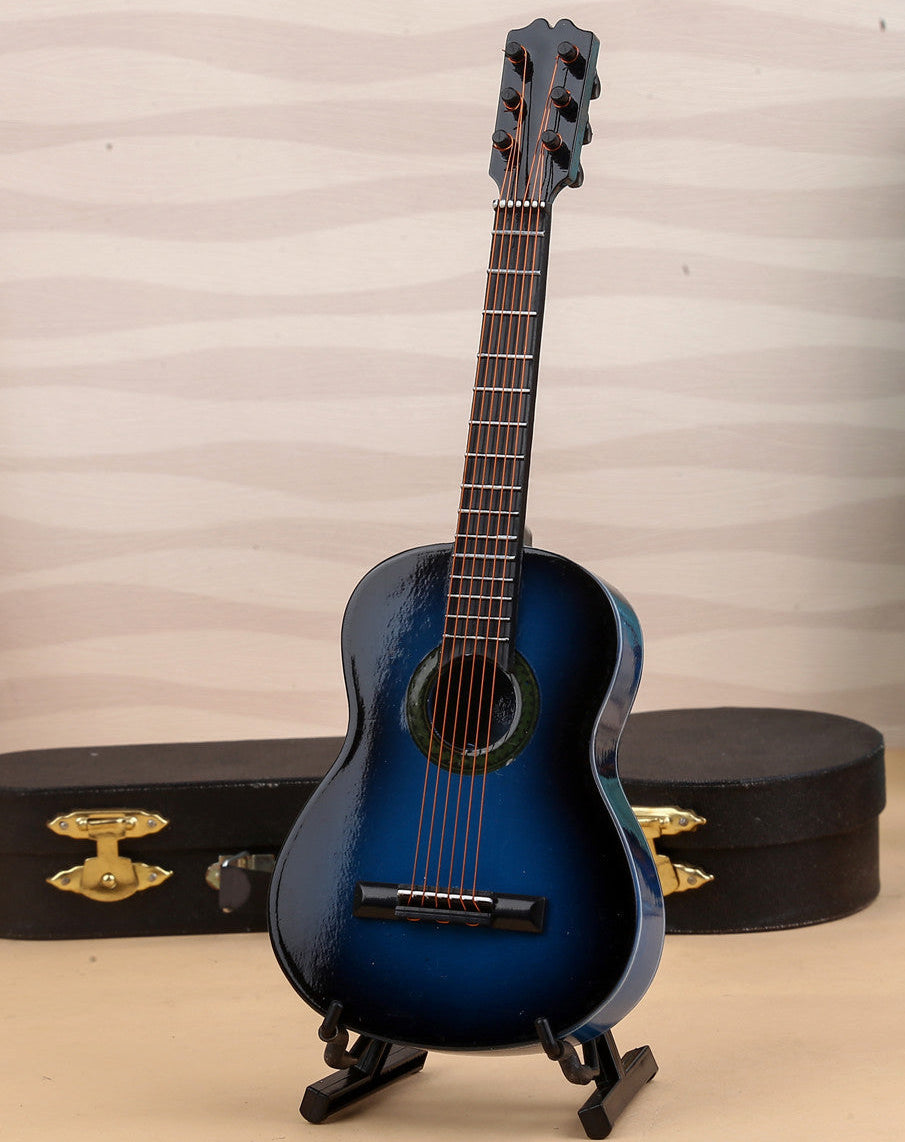 Blue acoustic guitar on a stand with a case and another guitar in the background.
