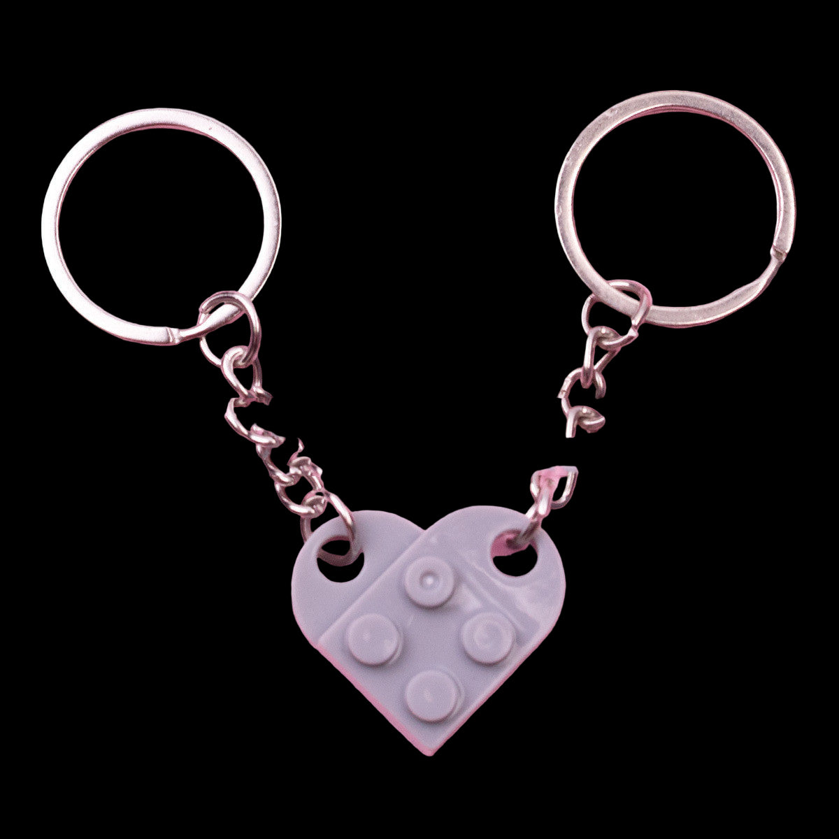 Gray heart-shaped keychain with silver rings on a pink background