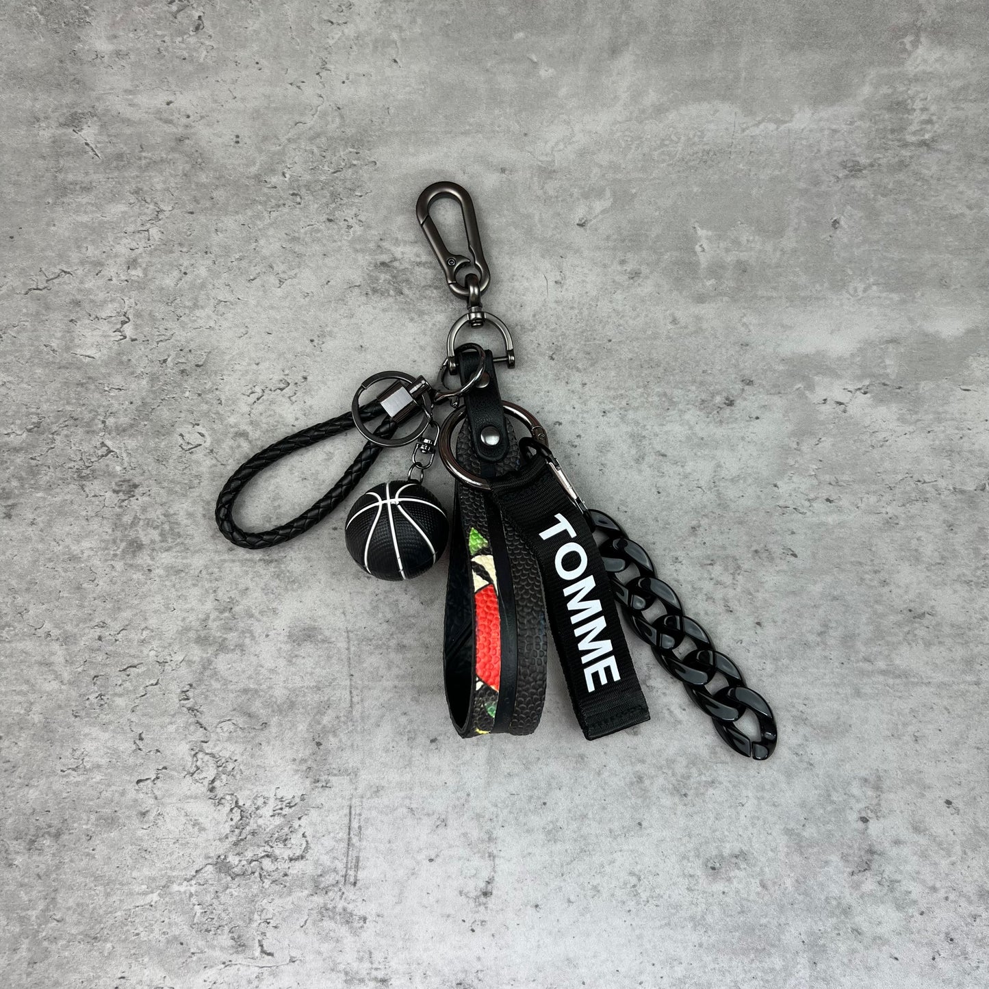 Keychain with basketball and 'Tommy' branding on a concrete surface