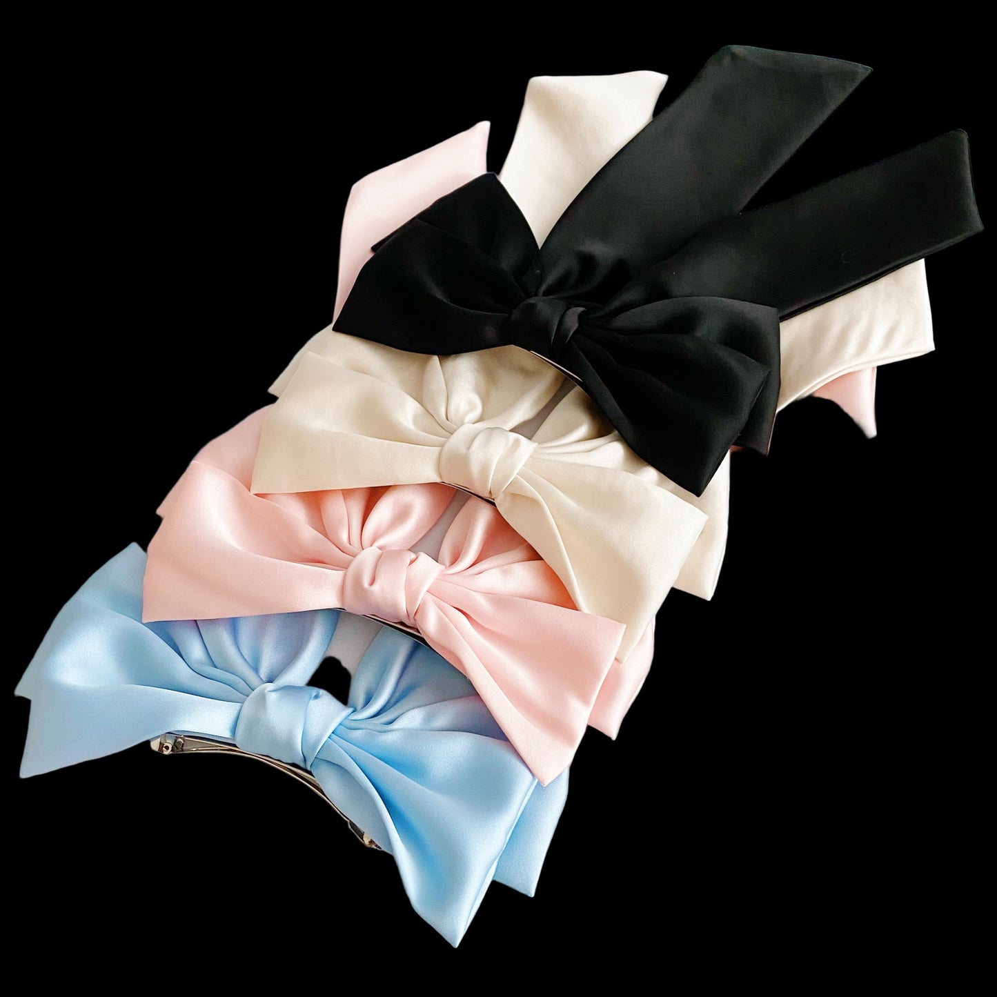 Set of colorful satin hair bows on a light wooden surface