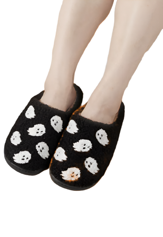Black slippers with white skull patterns worn indoors on a checkered floor.