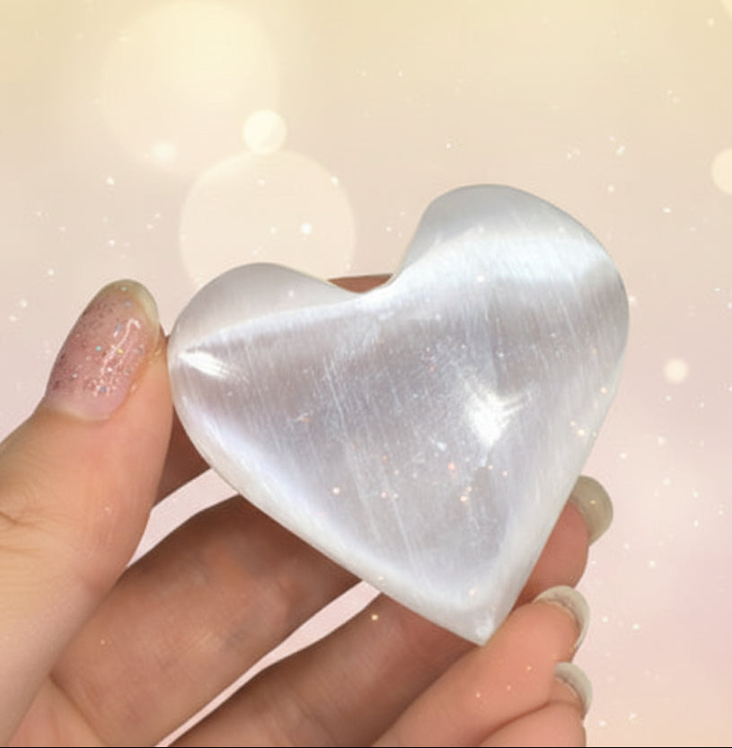 Heart-shaped crystal held in a hand against a dark background