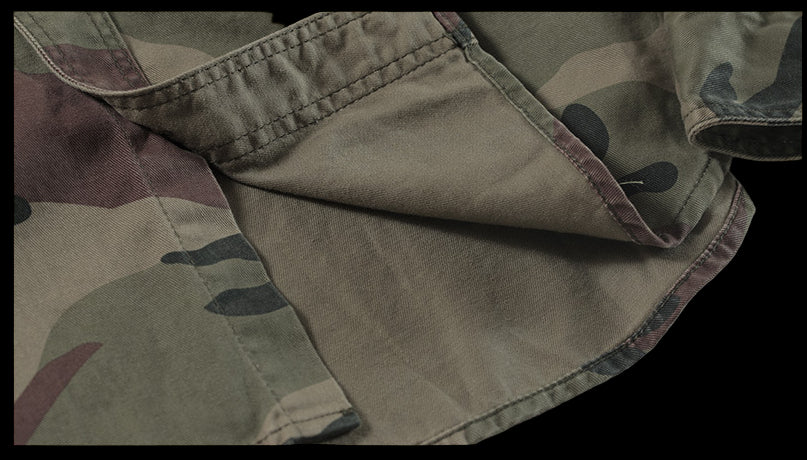 Close-up of camouflage fabric with visible stitching on a gray background