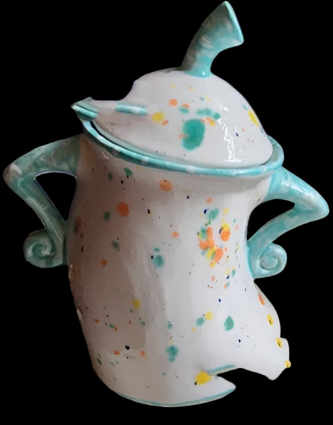 Ceramic mug with colorful speckles and turquoise handles on a kitchen counter.