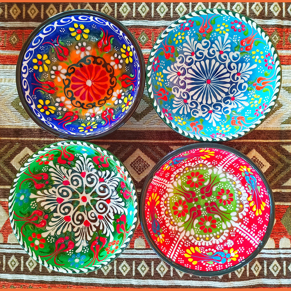 Four colorful decorative plates with intricate patterns on a patterned fabric background.