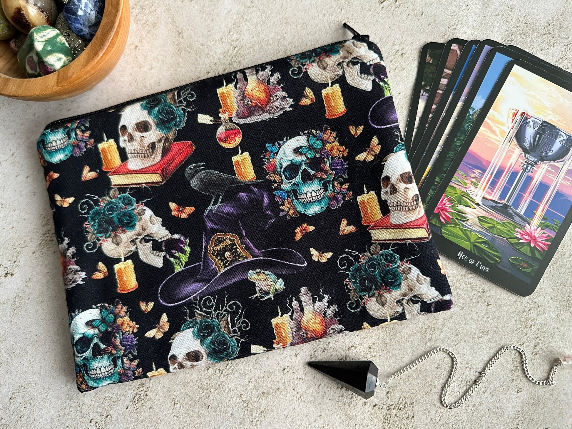 Colorful skull-themed pouch with tarot cards and crystals on a textured surface