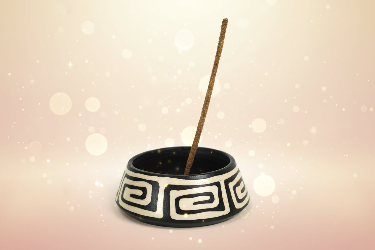 Ceramic incense burner with a decorative pattern and a single incense stick on a white background