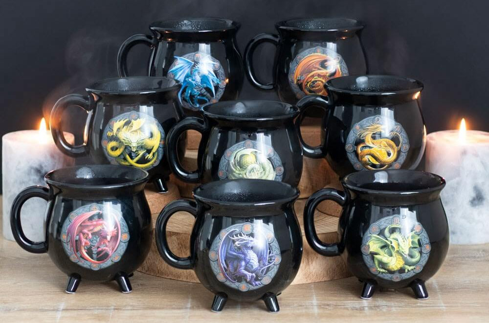 Set of black mugs with dragon designs on a wooden surface with candles in the background.
