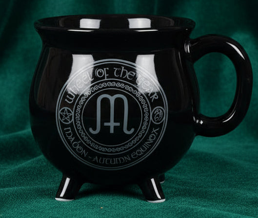 Black mug with a circular design featuring text and symbols on a white background