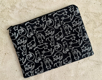 Black pouch with white cat pattern on a beige surface