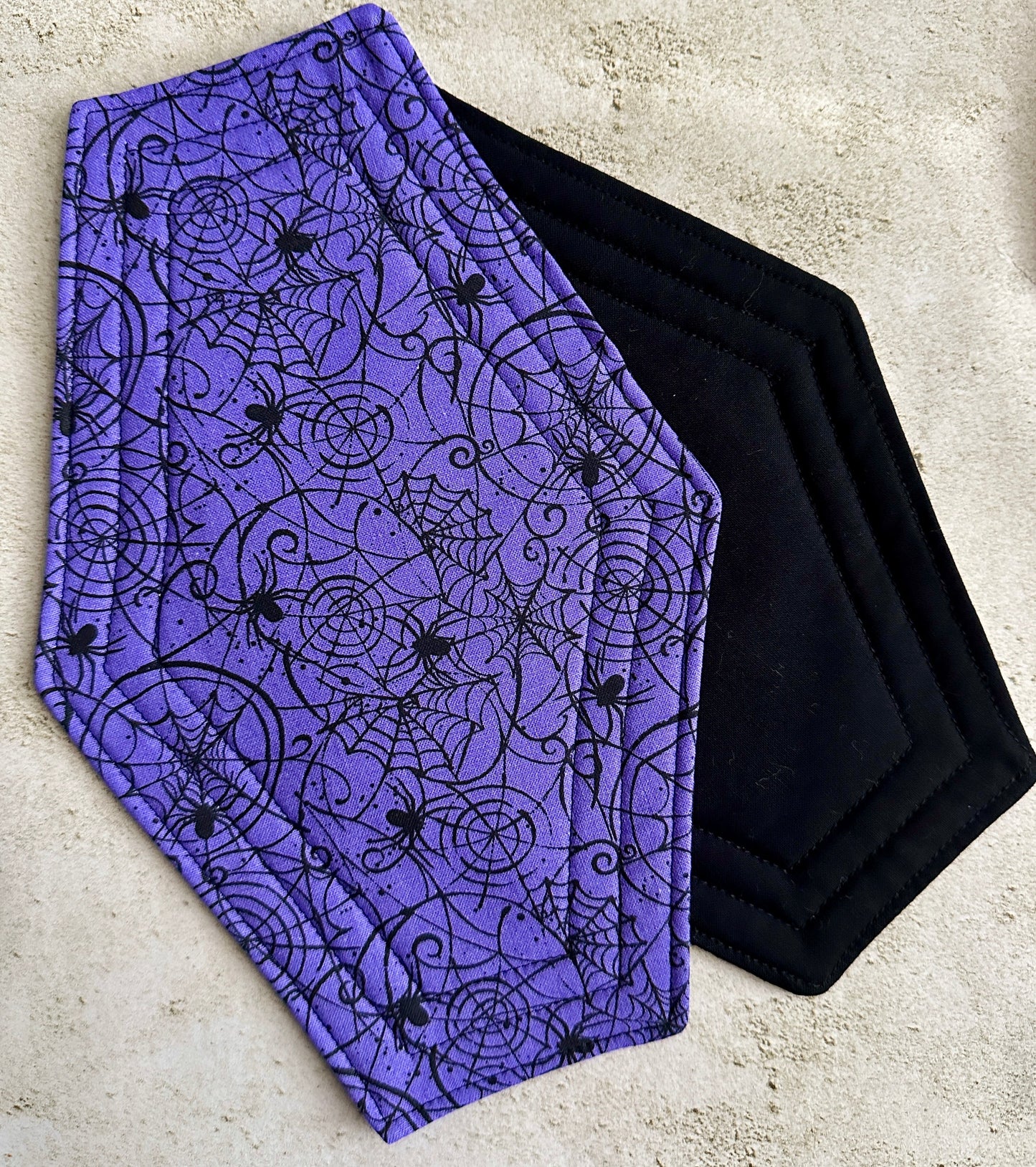Purple fabric with black spider web and spider pattern on a concrete surface