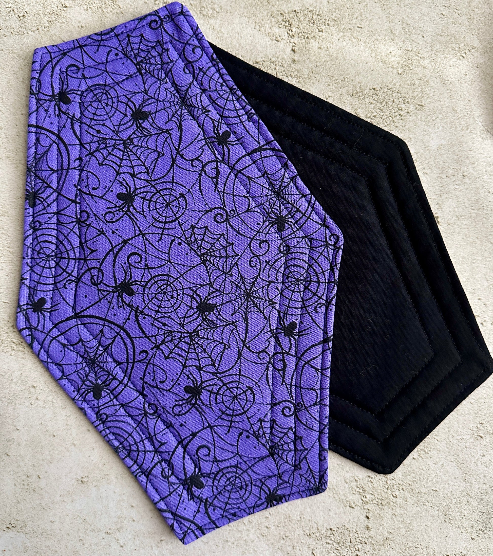 Purple fabric with black spider web and spider pattern on a concrete surface