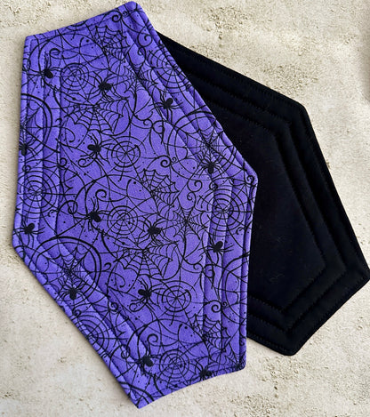 Purple fabric with black spider web and spider pattern on a concrete surface