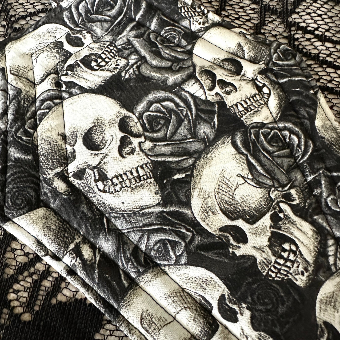 Black and white illustration of skulls and roses on a textured background