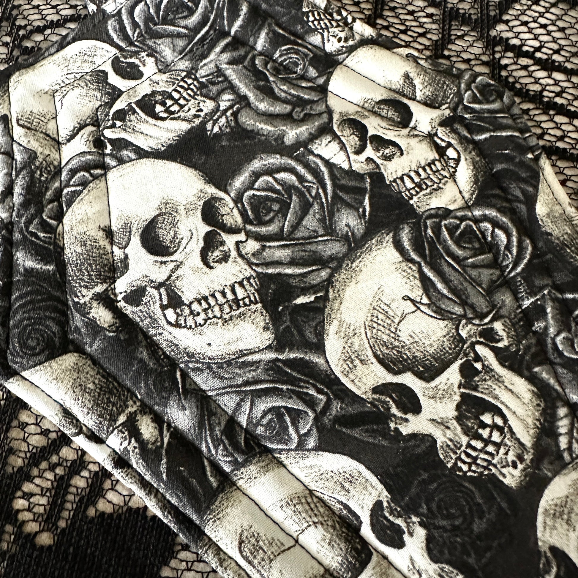 Black and white illustration of skulls and roses on a textured background