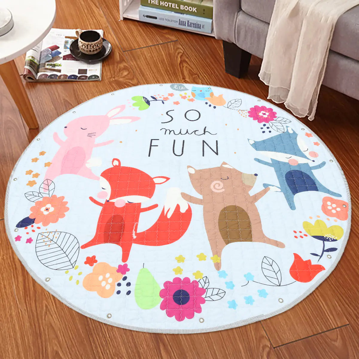 Round children's rug with animal illustrations and 'So Much Fun' text on a wooden floor.