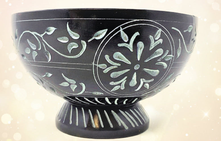 Black ceramic bowl with white floral patterns on a white background