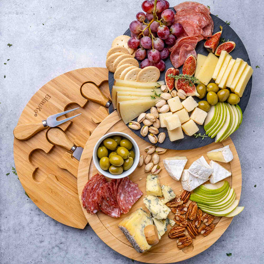 Assorted meats, cheeses, fruits, and nuts on a wooden cutting board with a gray background.