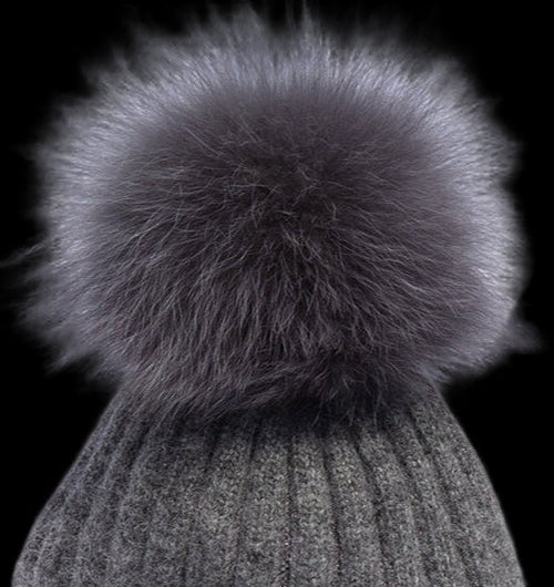 Gray knitted beanie with a large fur pom-pom on a white background