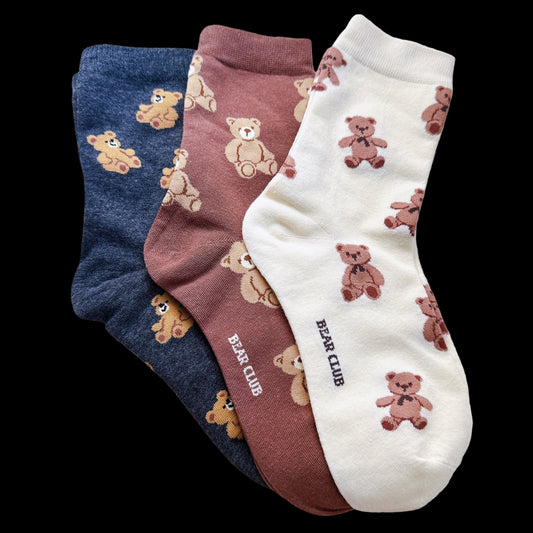 Three pairs of socks with teddy bear patterns on a light gray background