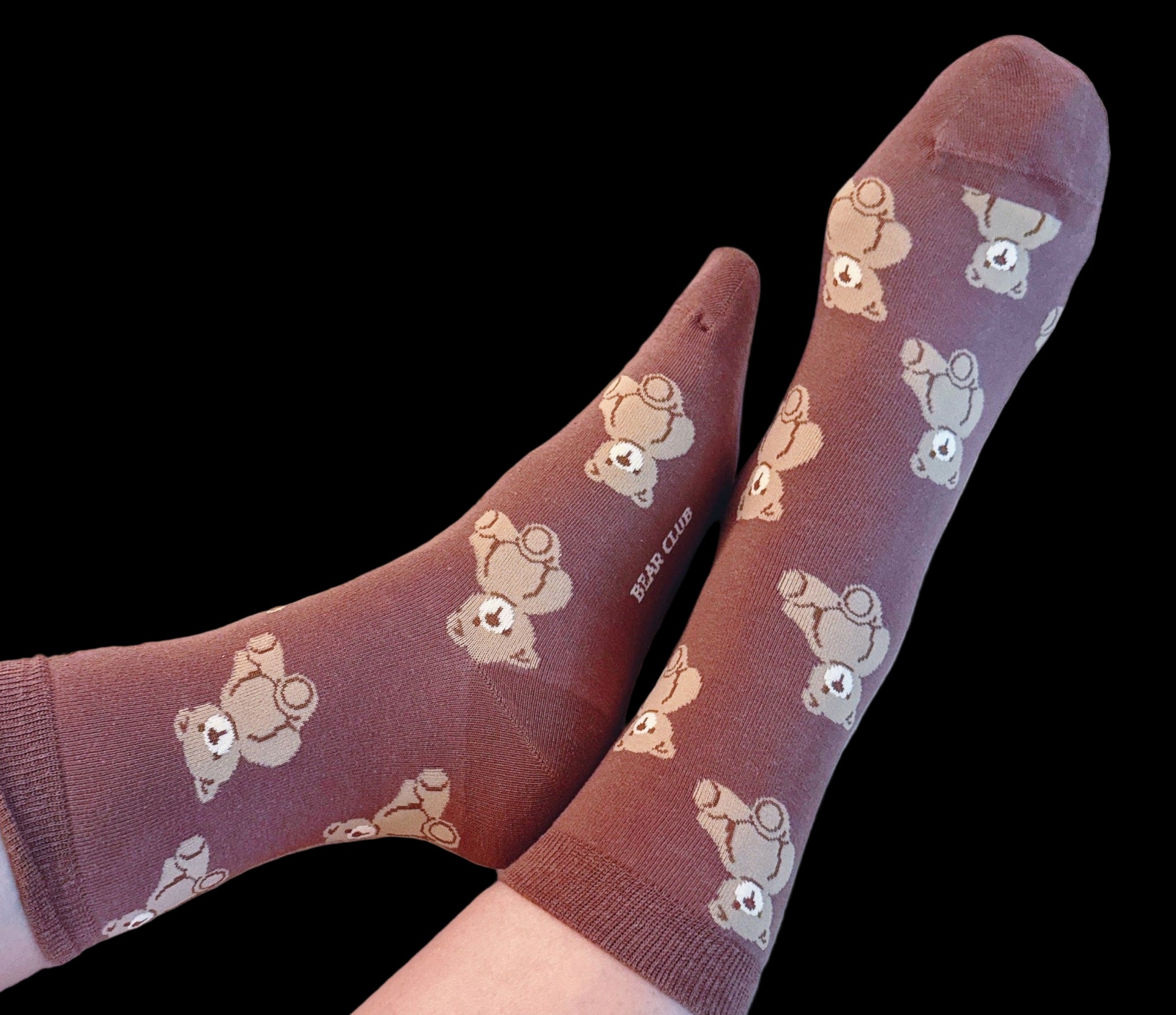 Brown socks with teddy bear pattern worn by a person on a light background