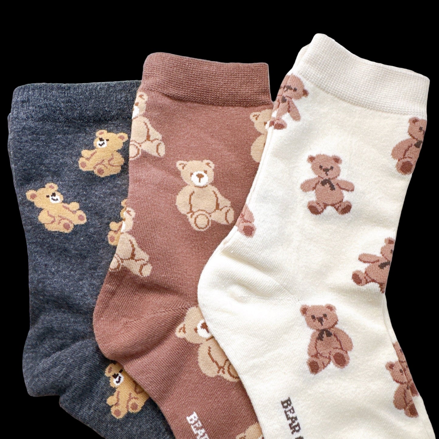Three pairs of socks with teddy bear patterns on a light background