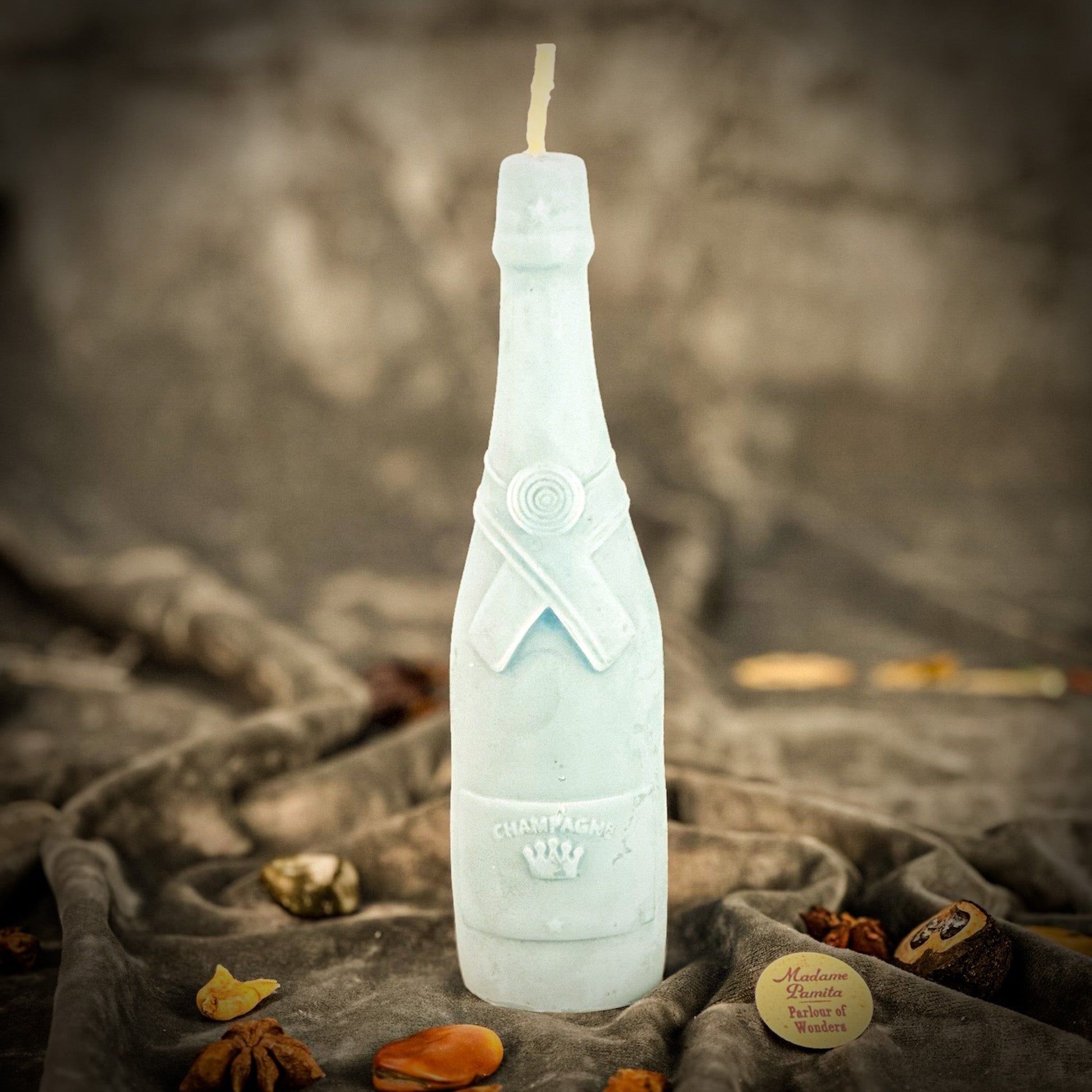 Frosted bottle-shaped candle on a textured surface with a blurred background