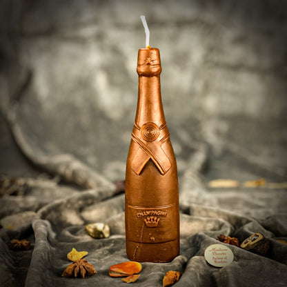 Candle shaped like a champagne bottle on a textured surface with a blurred background