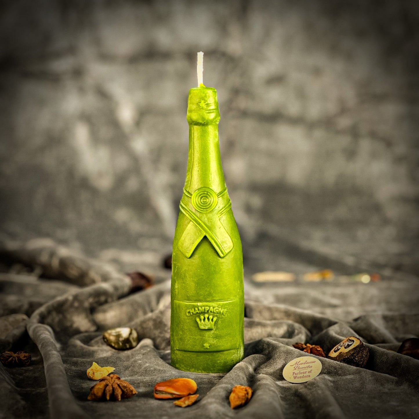 Green bottle-shaped candle on a textured surface with a blurred background