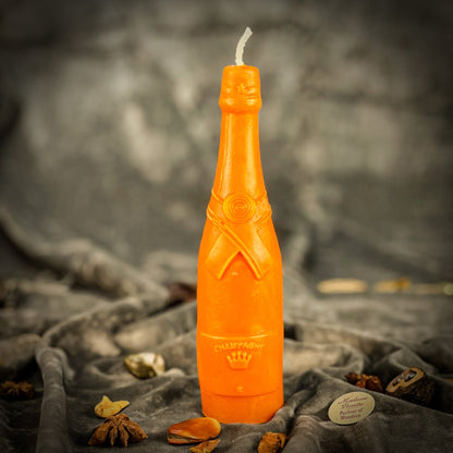 Orange bottle-shaped candle on a textured surface with a blurred background