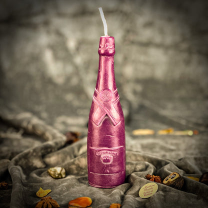Pink bottle-shaped candle on a textured surface with a blurred background