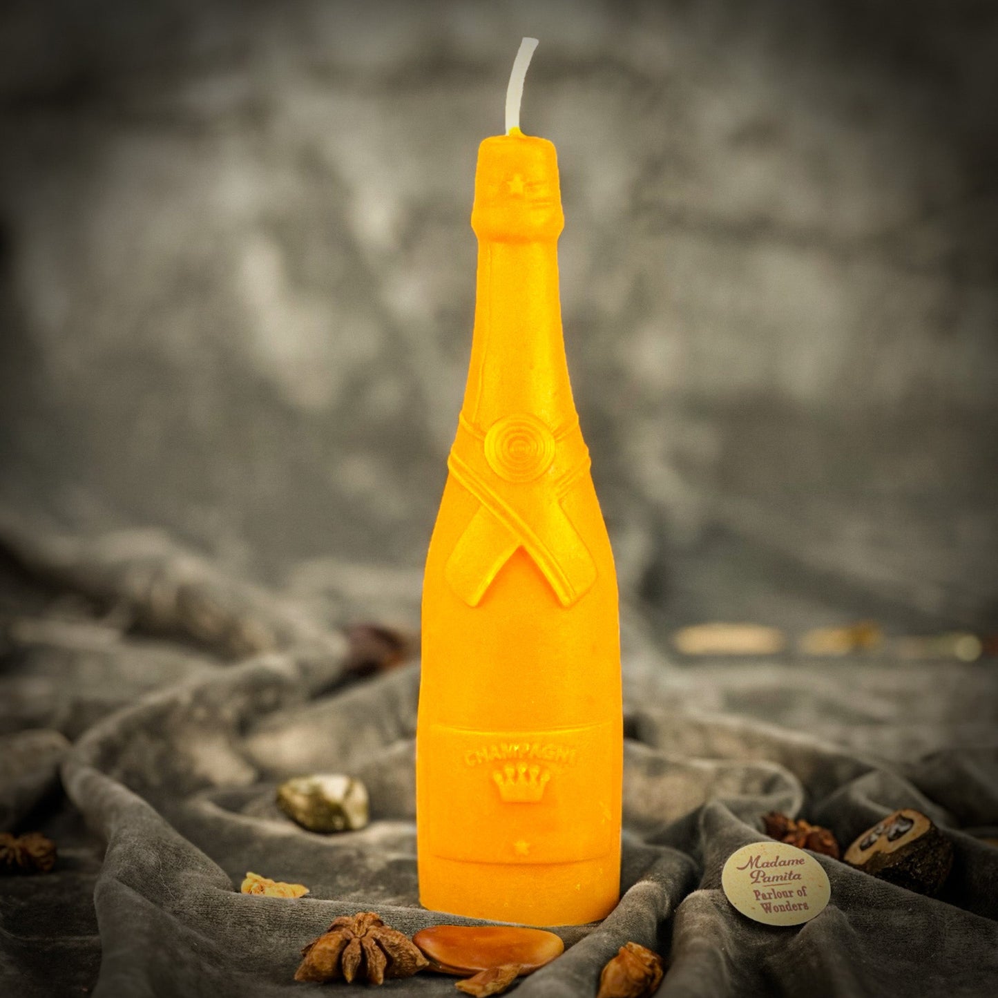 Yellow bottle-shaped candle on a textured surface with a blurred background