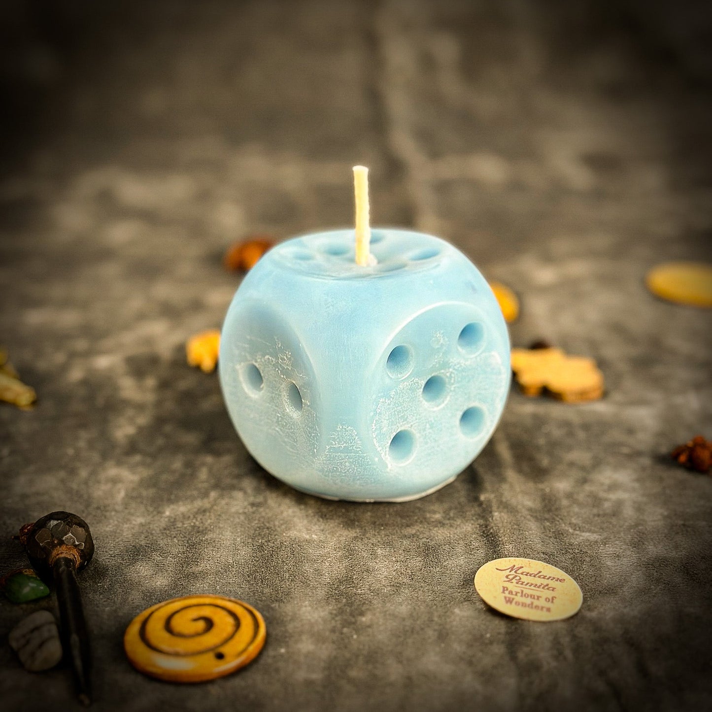Blue dice-shaped candle with decorative elements on a textured surface