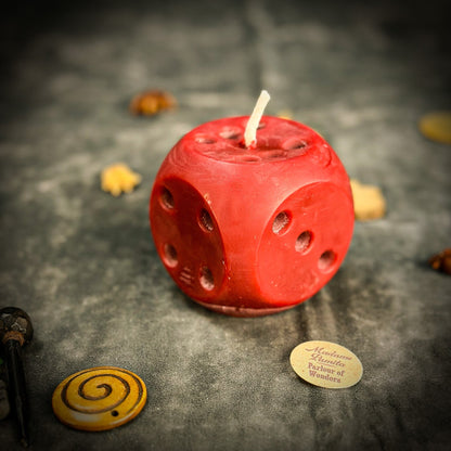 Red dice-shaped candle with small yellow candles on a dark textured surface