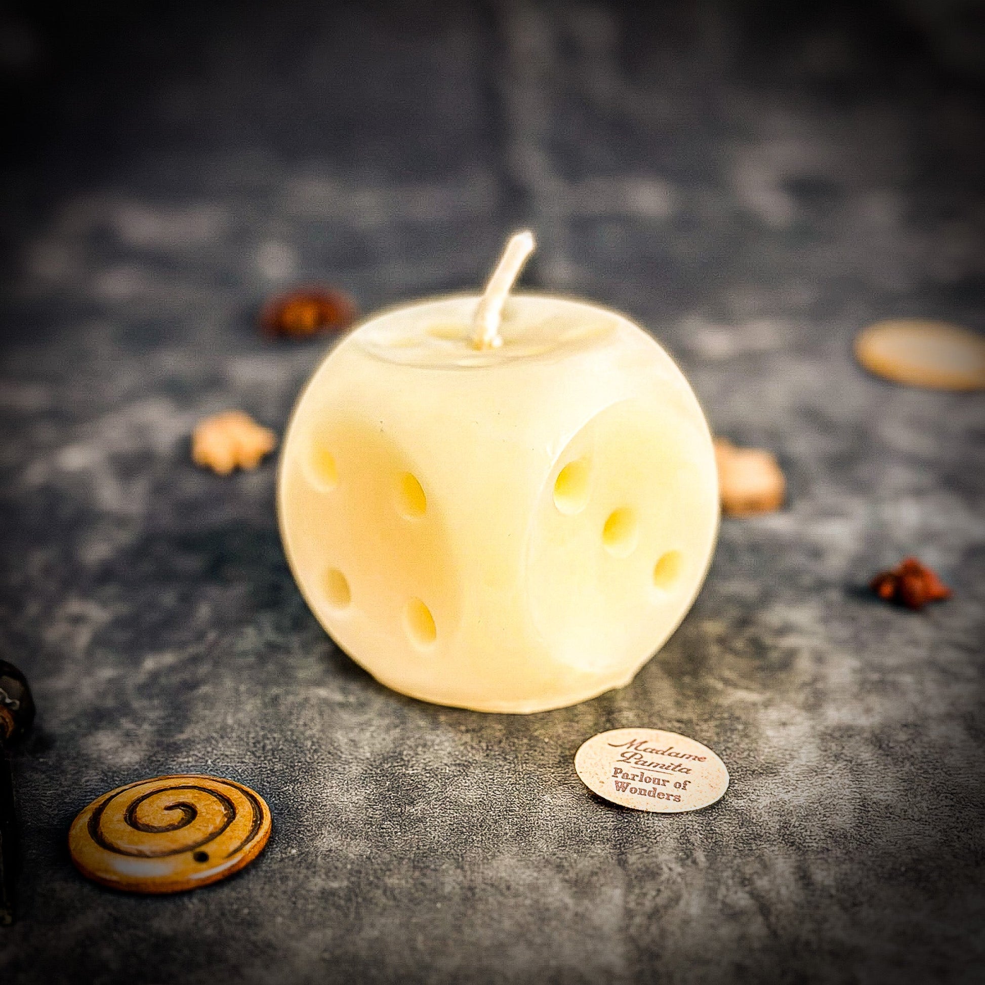 Candle shaped like a dice with decorative elements on a dark surface