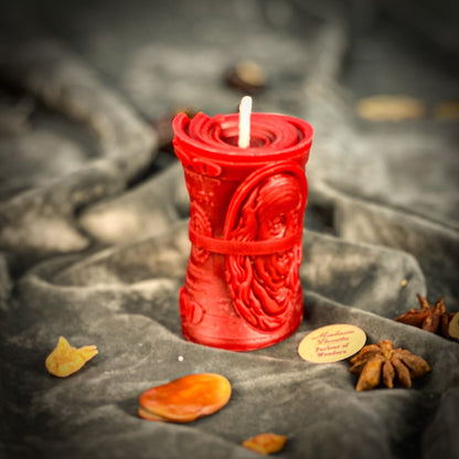 Red candle with intricate design on a dark fabric background