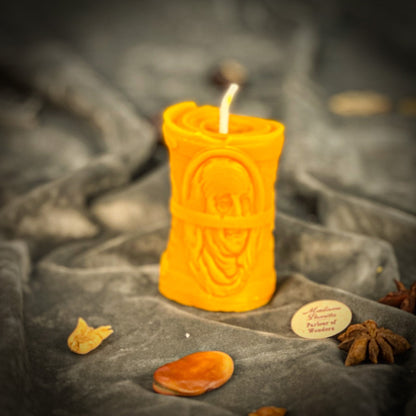 Decorative candle with intricate design on a stone surface with dried fruits and spices.