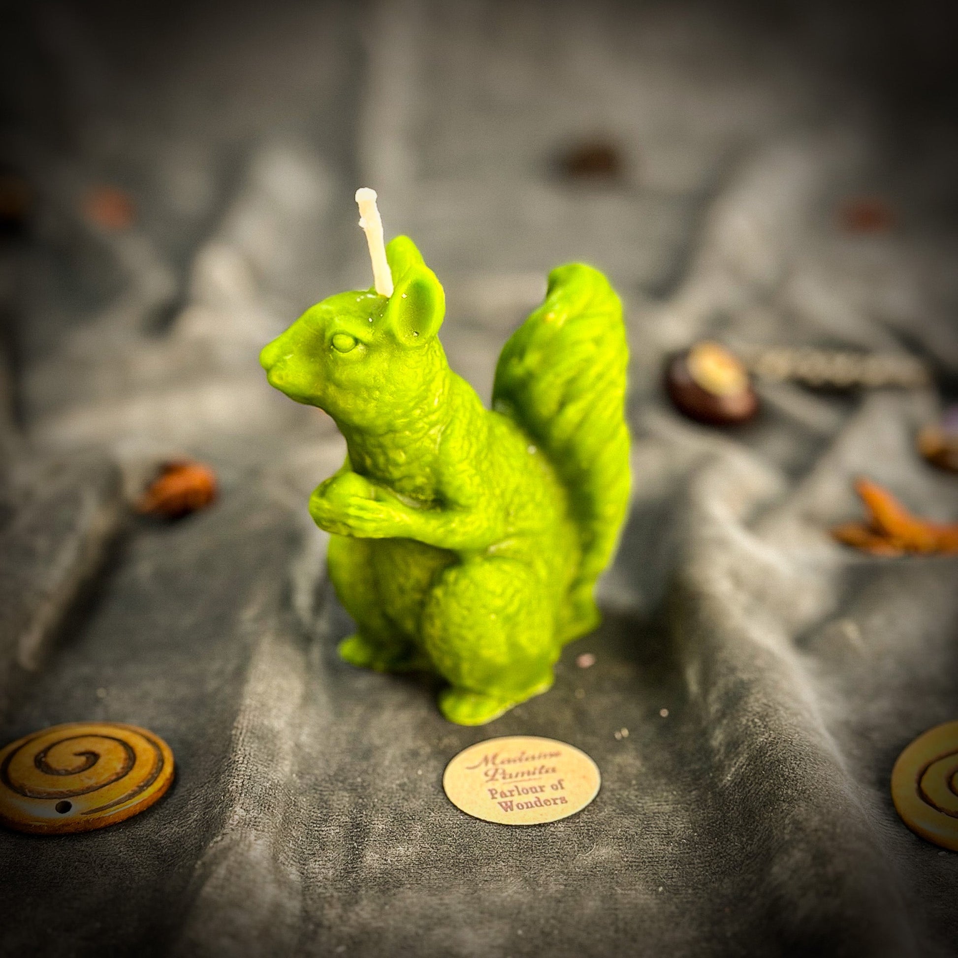 Green squirrel-shaped candle on a textured surface with blurred background