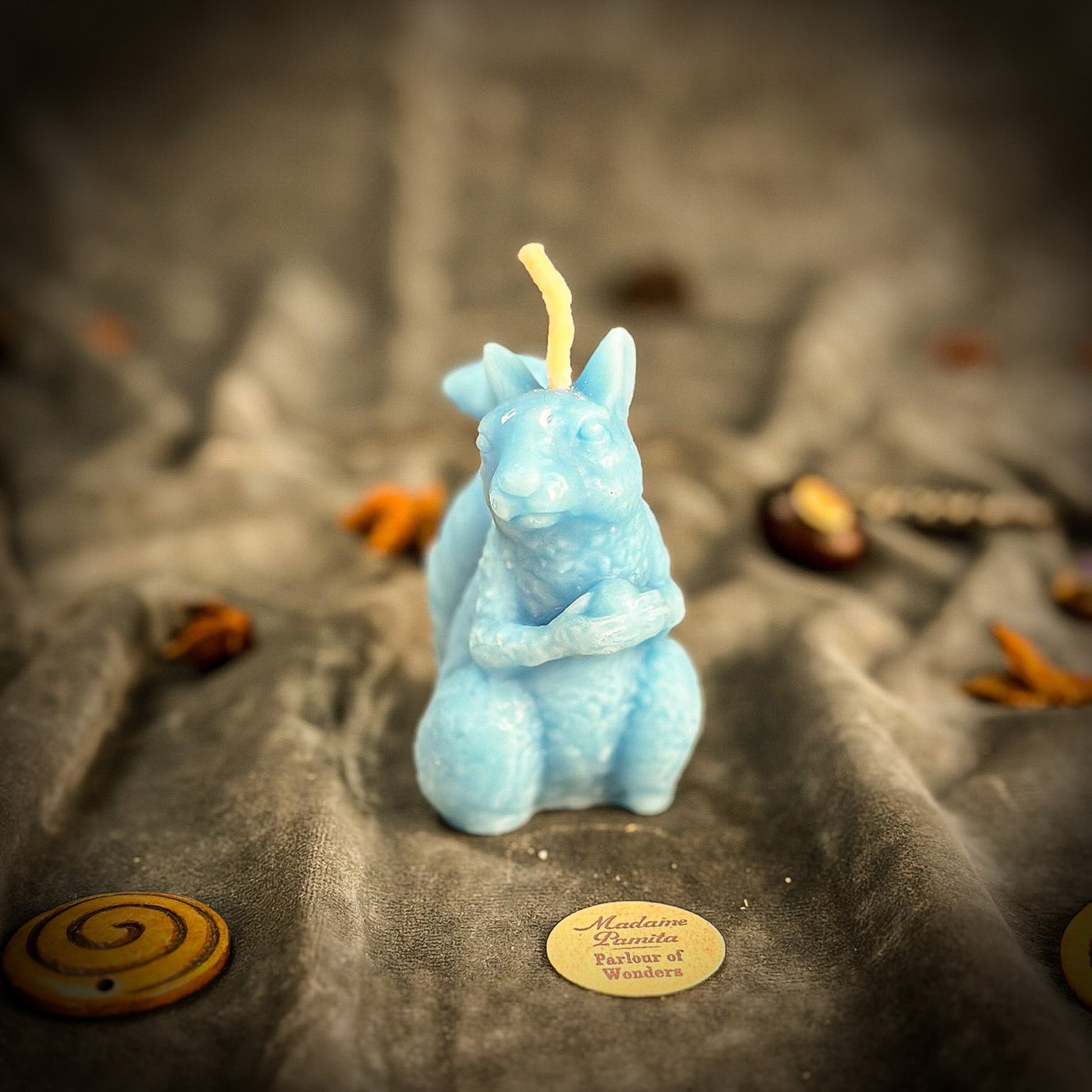 Blue squirrel-shaped candle on a textured surface with a blurred background