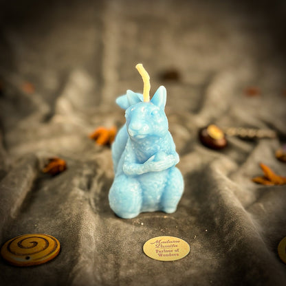 Blue squirrel-shaped candle on a textured surface with a blurred background