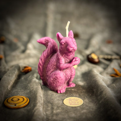 Pink squirrel-shaped candle on a stone surface with blurred background