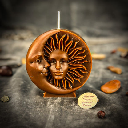 Candle with sun and moon design on a dark surface