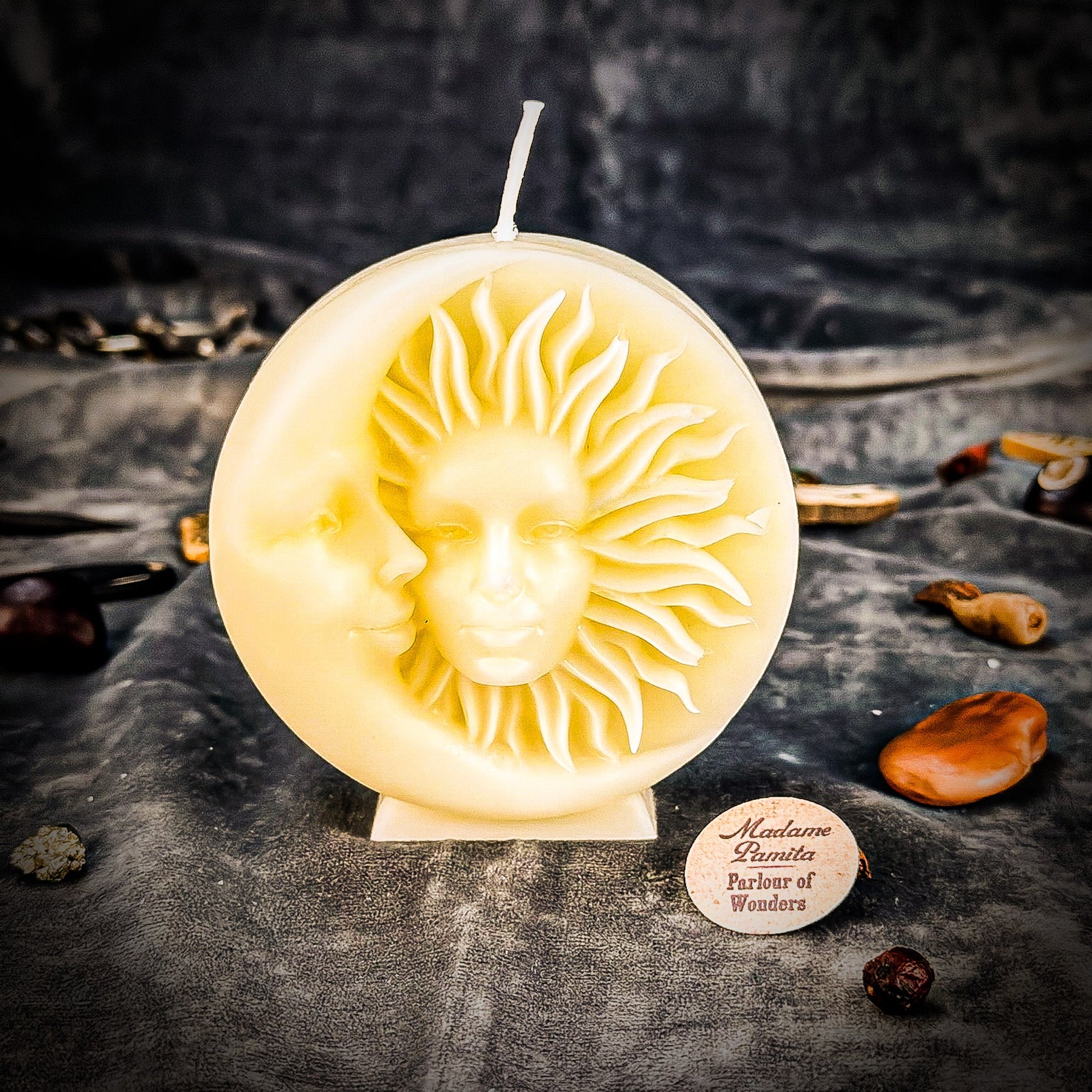 Decorative candle with sun and moon design on a dark surface