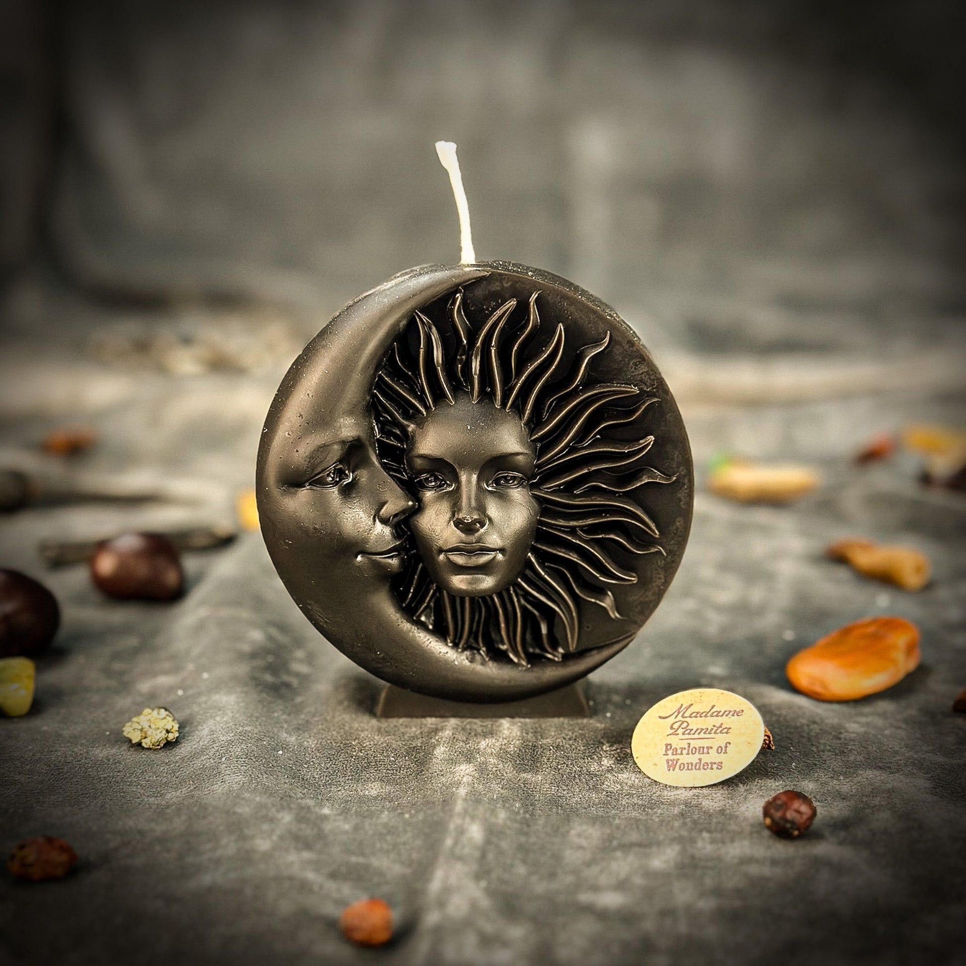 Decorative candle with sun and moon design on a dark surface