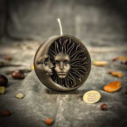 Decorative candle with sun and moon design on a dark surface