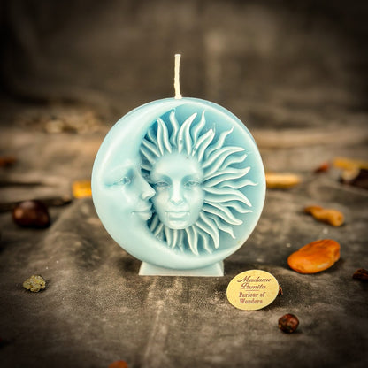 Decorative candle with sun and moon design on a dark surface, featuring a brand label.