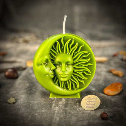 Green sun and moon candle on a dark surface with a brand label.